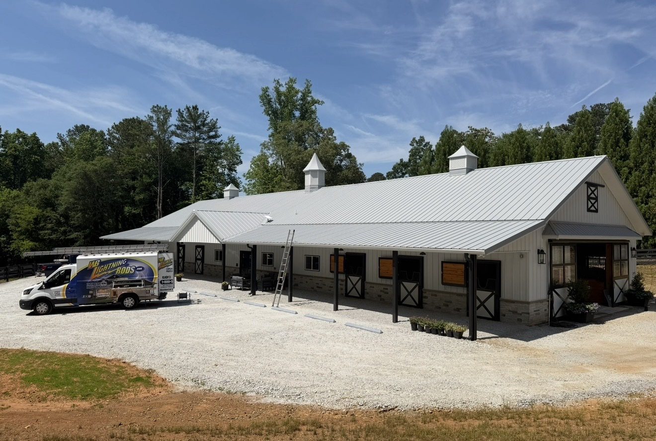 White stable building with a cupola on a horse farm fitted with lightning protection